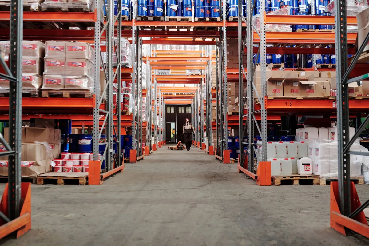 Warehouse storage aisle with goods on metal racks.